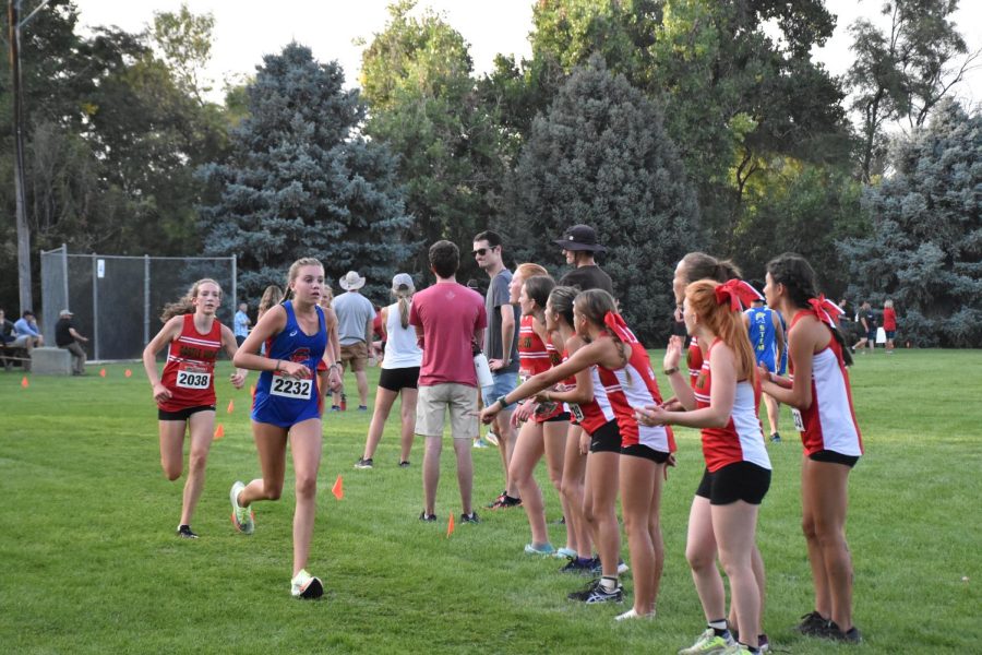 Castle View girls cheer on junior Reese Plummer as she chases the runner in front of her in the races final sprint. In the last hundred meters, Plummer beat her competitor to win fourth place.