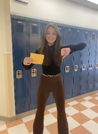 Student Maddie Hobbs holding the new travel Advisement passes that students are required to take with them in order to go in the halls. Because most students are not a fan of these passes, she is thumbing it down.