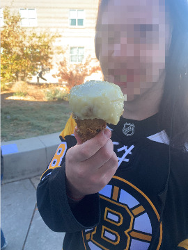 A student holds a chicken wing with mashed potatoes on top, like an ice-cream cone.